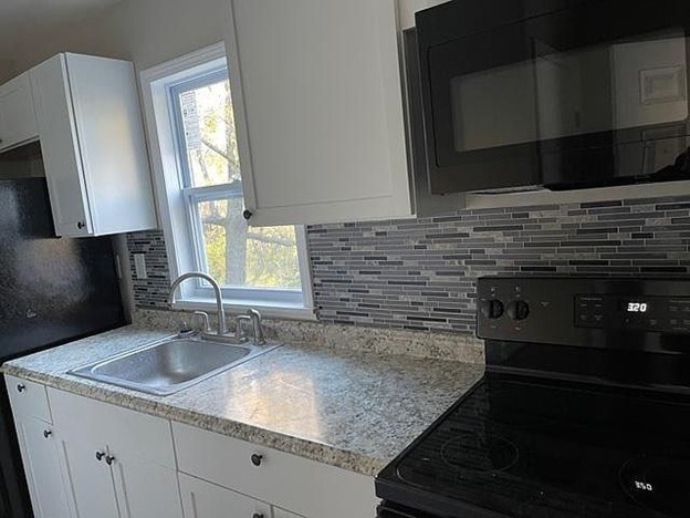 A kitchen with black appliances and white cabinets.