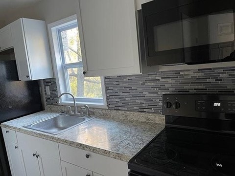 A kitchen with black appliances and white cabinets.
