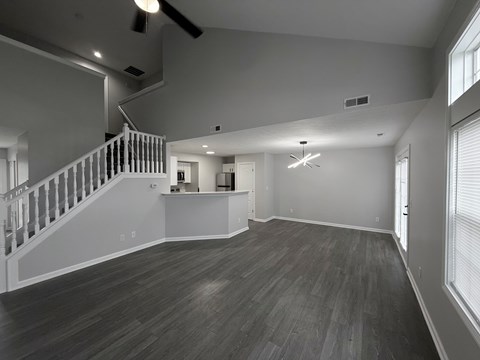 A spacious room with a staircase and a ceiling fan.