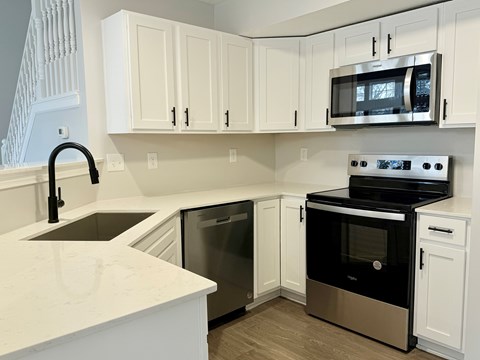 A kitchen with white cabinets and a black oven.