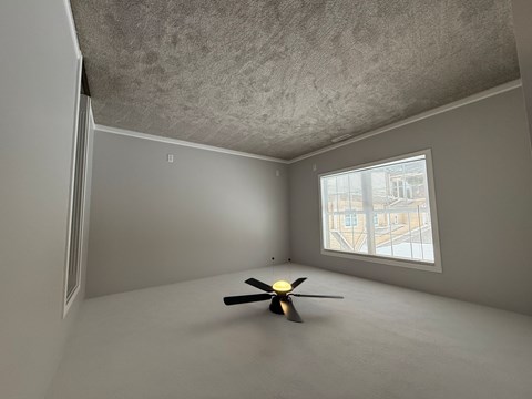 A room with a ceiling fan and a window.