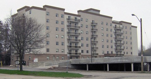 A large apartment building with a parking garage in front.