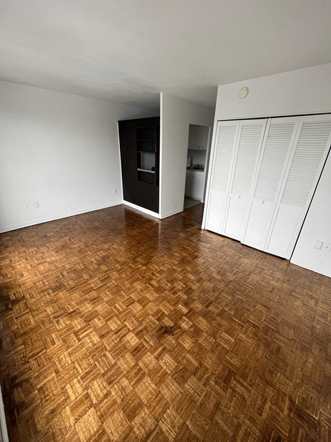 an empty living room with wood flooring and a closet