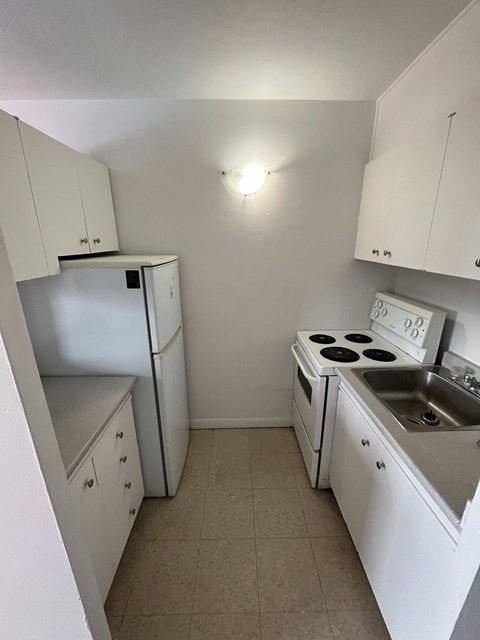 an empty kitchen with white appliances and white cabinets
