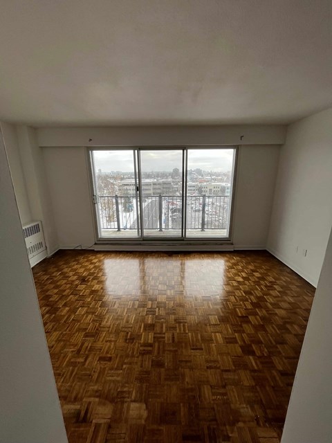an empty living room with wood floors and a large window