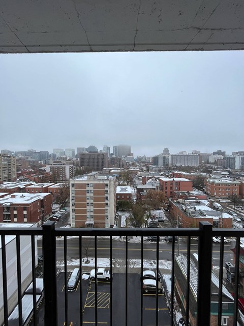 a view of a city from a balcony with a black railing
