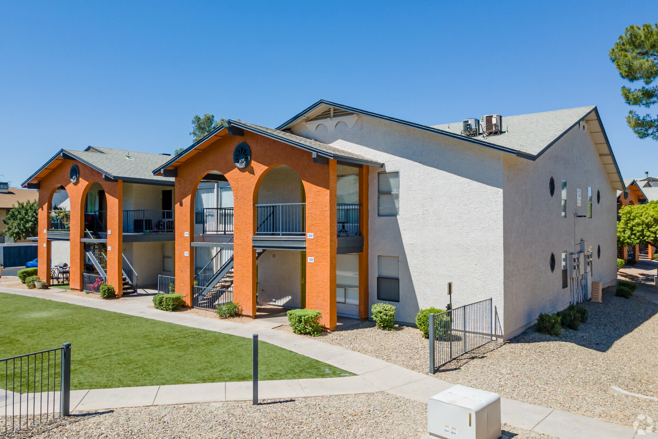 an apartment building with orange brick and white walls and a lawn