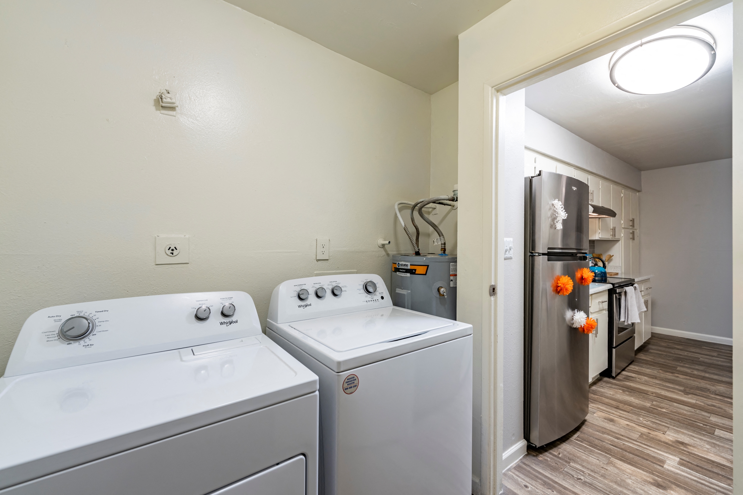 an empty laundry room with two washes and a refrigerator
