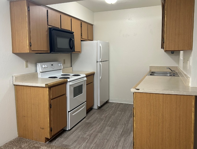 an empty kitchen with white appliances and wooden cabinets