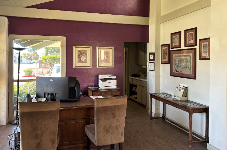 an office with a desk with a computer and chairs and a window