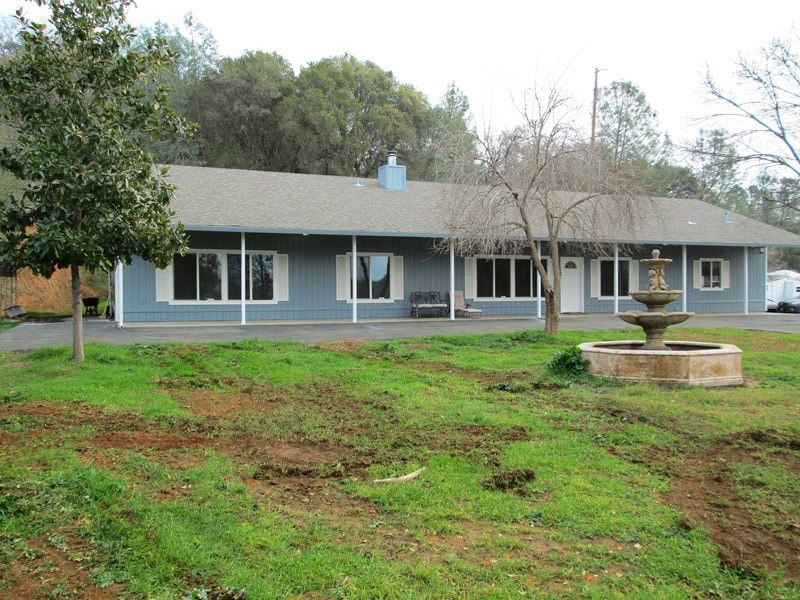 A house with a grey roof and a fountain in front.