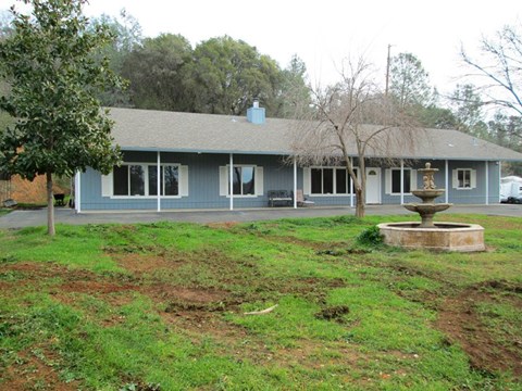 A house with a grey roof and a fountain in front.
