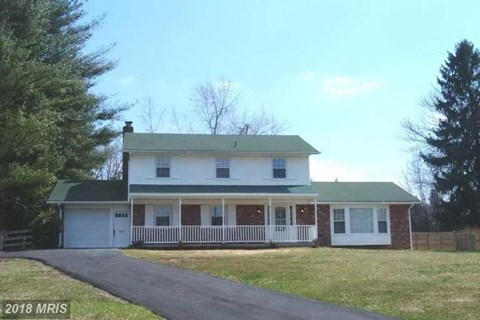 a white house with a porch and a driveway