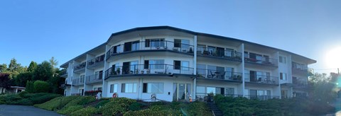 A sunny day at a white apartment building with balconies.