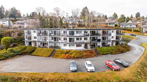 A large white building with a parking lot in front.
