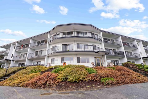 A large white building with balconies and a red door.