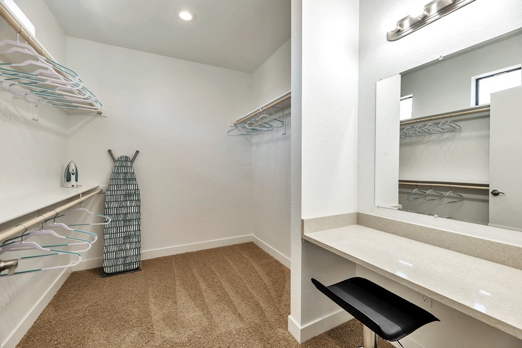 a closet with a dresser and a mirror and a dress