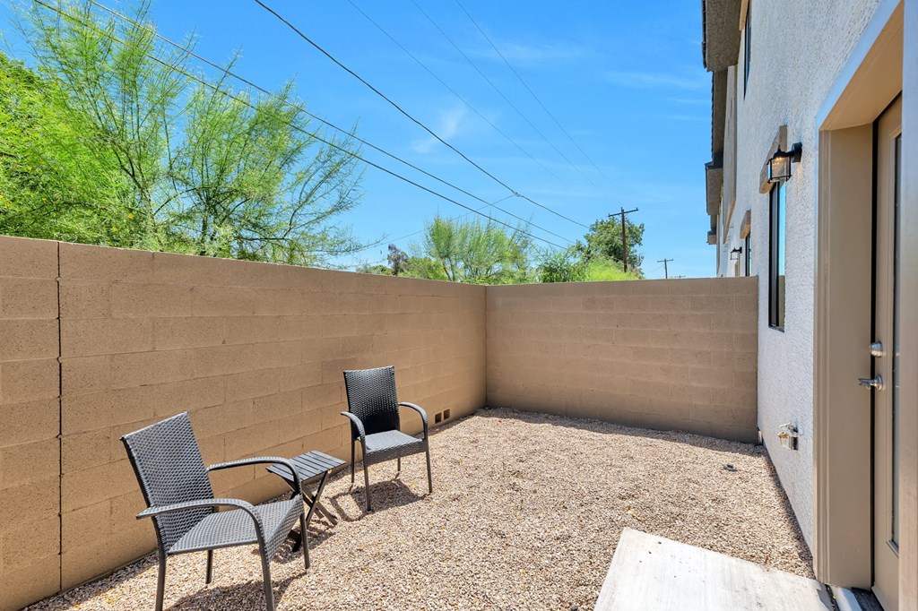 the backyard has a seating area with chairs and a privacy wall