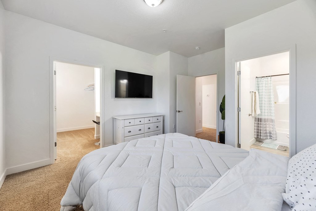 a bedroom with a large white bed and a tv