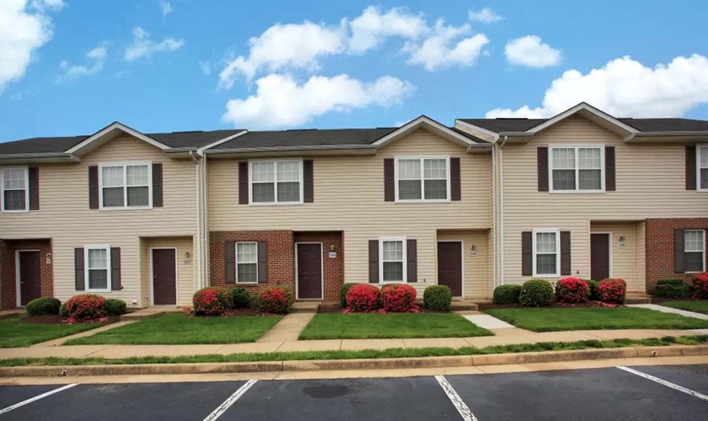 an apartment building with a lawn and shrubs in front of it
