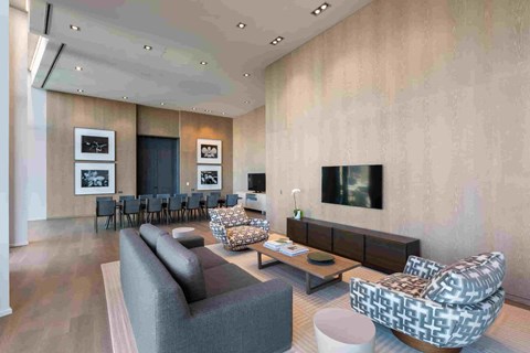 A modern living room with a grey sofa, a patterned armchair, and a television mounted on the wall.
