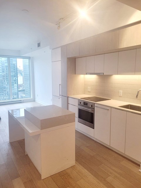 A kitchen with white cabinets and a wooden floor.