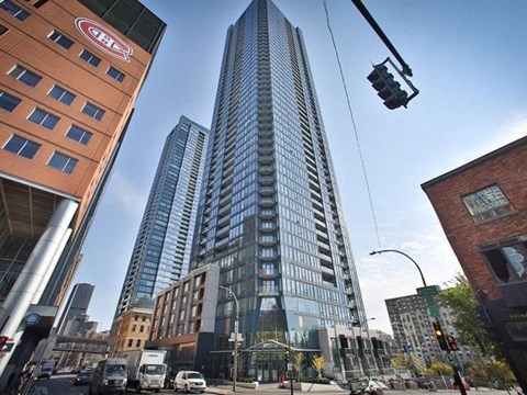 A tall building with the logo "GEL" on the top stands in the middle of a city street.