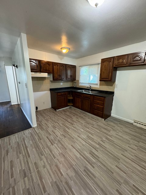 an empty kitchen with wooden floors and wooden cabinets