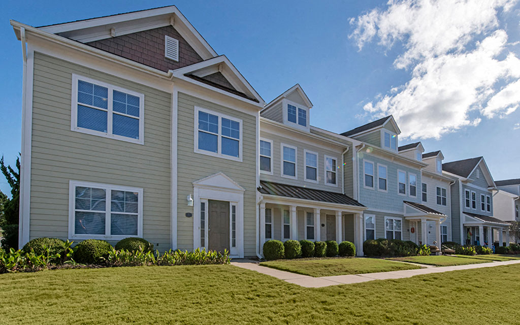 a row of town homes with grass and a sidewalk