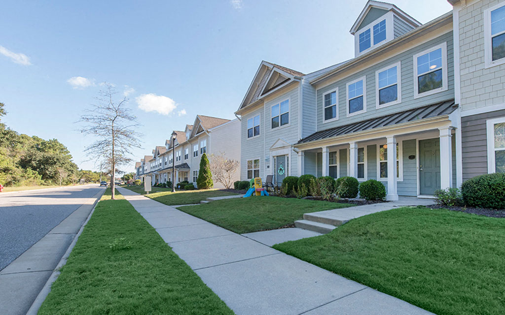 a row of white houses on the side of a sidewalk
