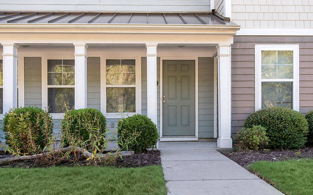 the front of a house with a blue door and a sidewalk