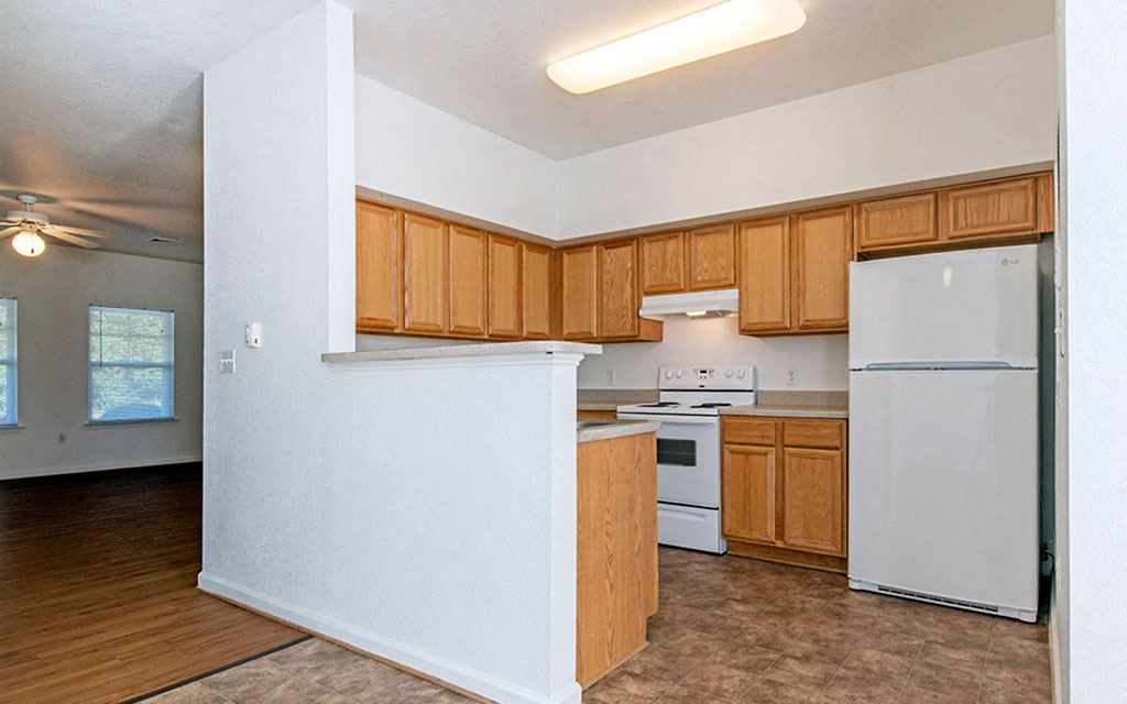 an empty kitchen with white appliances and wooden cabinets