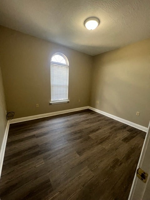 an empty room with a window and wooden floors