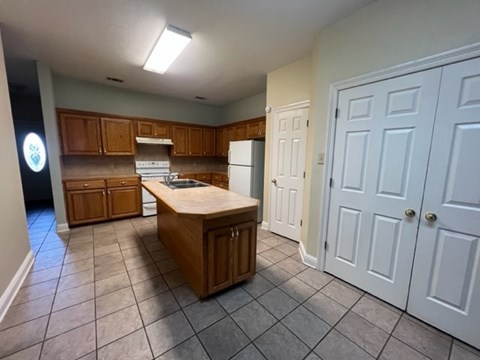 A kitchen with a white refrigerator and wooden cabinets.