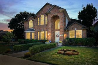 the front yard of a brick house with a flower arrangement in the grass