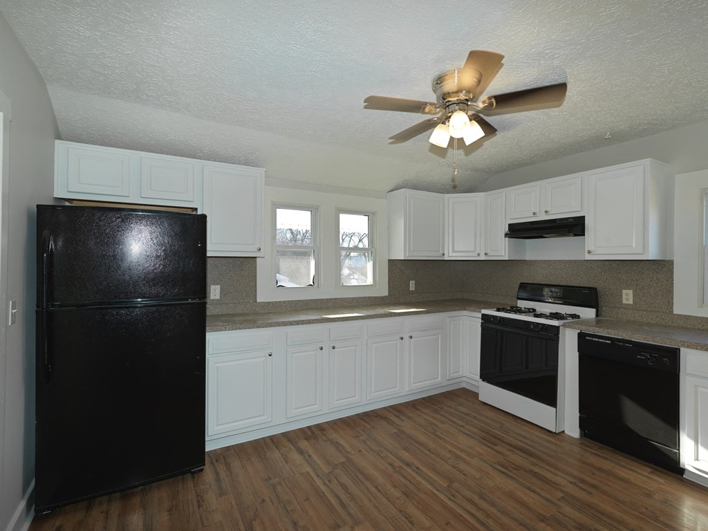 A kitchen with black appliances and white cabinets.