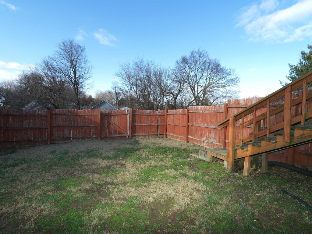 A backyard with a wooden fence and a small wooden deck.