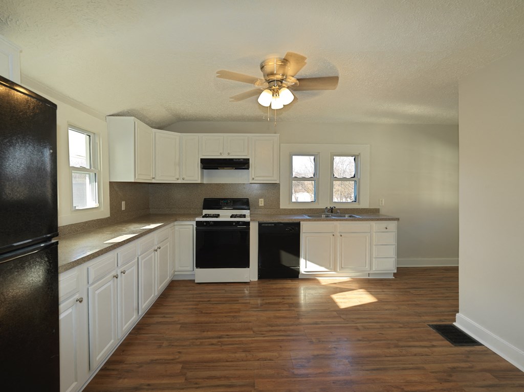 A kitchen with a black refrigerator and white cabinets.