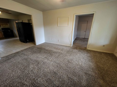 a living room with a carpeted floor and a door to a bedroom