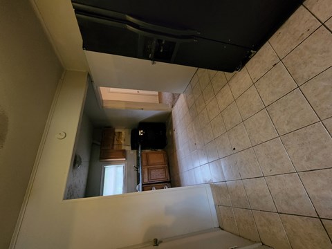 the view from the top of the stairs looking down into the kitchen of a house