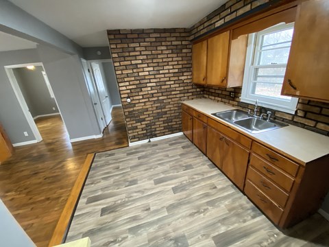 A kitchen with wooden cabinets and a brick wall.