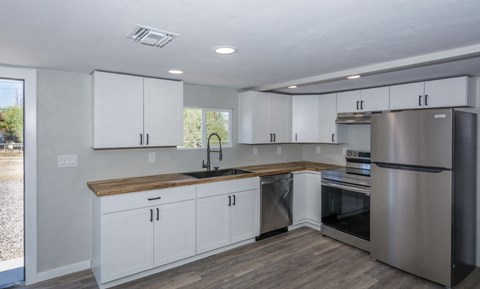 A kitchen with white cabinets and a wooden counter.