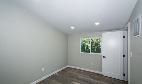 A room with a white door and a window showing greenery outside.