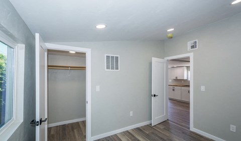 A room with a doorway leading to a kitchen and a window on the left.