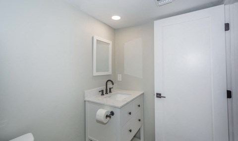 A white bathroom with a sink and mirror.