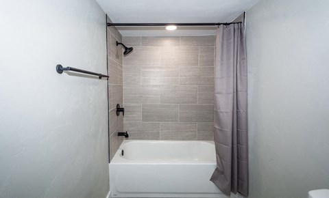 A white bathtub with a grey shower curtain in a bathroom.