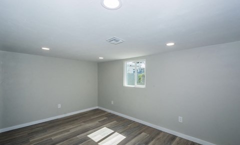 A room with a window and a wooden floor.