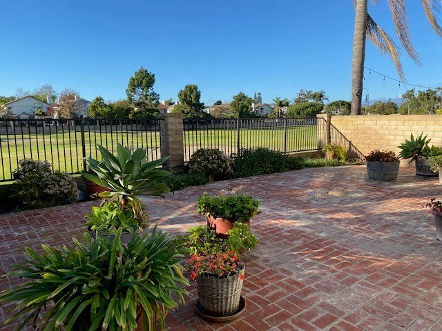 a brick patio with potted plants in front of a fence