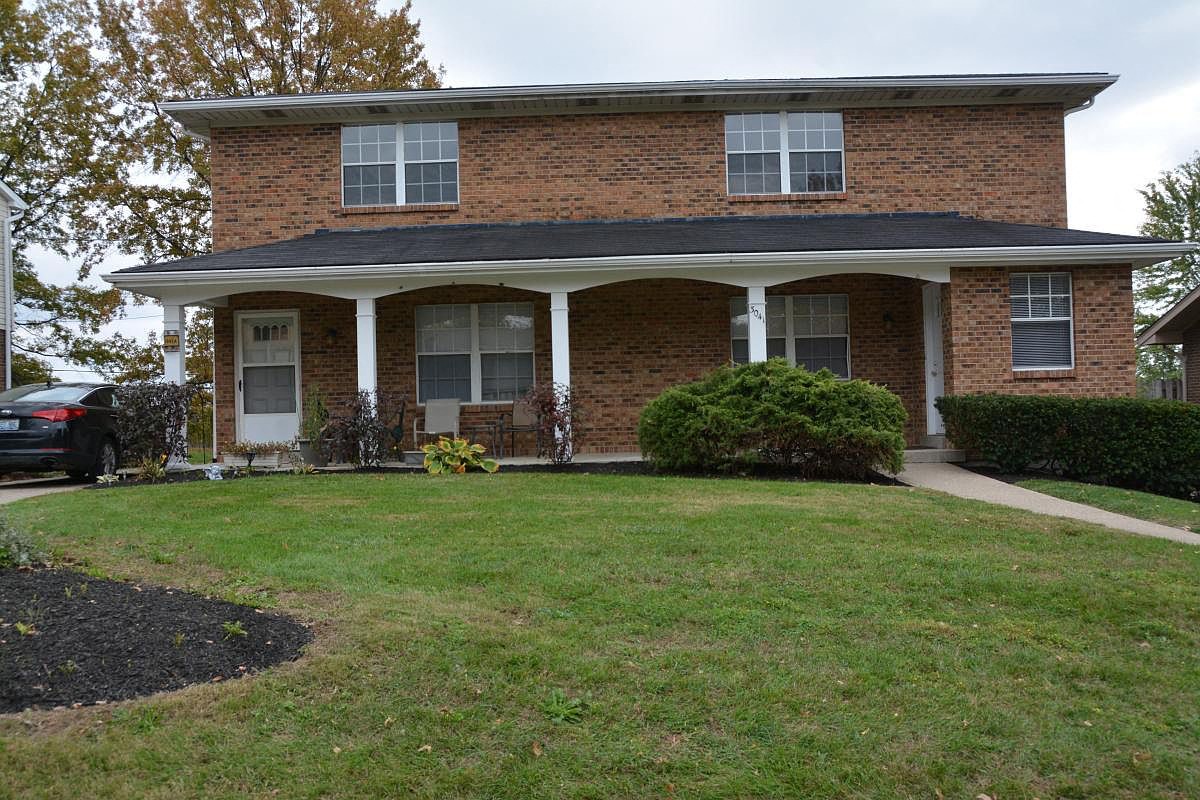 a brick house with a porch and a lawn