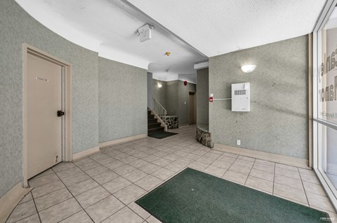 A hallway with a green rug on the floor and a white door on the left.